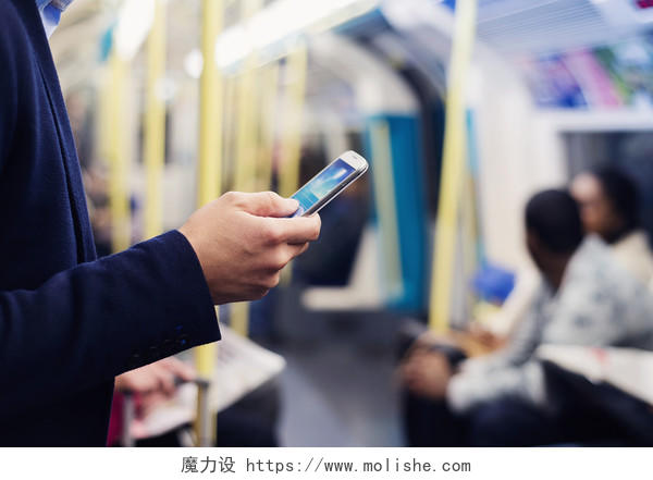 年轻英俊的商人在地铁玩手机
